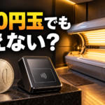 「500円玉でも使えない？」と書かれ、500円玉とキャッシュレス決済端末、奥にタンニングマシンが写った画像